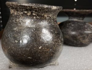 Photograph of a black ceramic vessel with chipped pigment