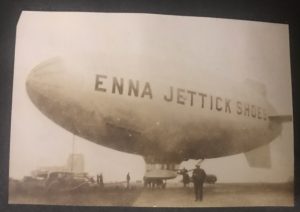 A black and white photograph of a blimp with "Emma Jettick Shoes" printed on the side