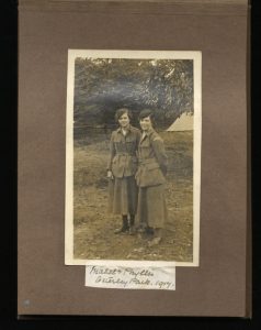 scanned image of a scrapbook page with a photo of two women in WWI uniforms and caption with their names below